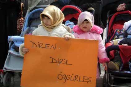 2 yaşındaki kızın başına türban, eline pankart